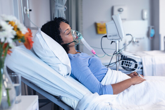 Sleeping african american female patient in hospital bed with oxygen ventilator