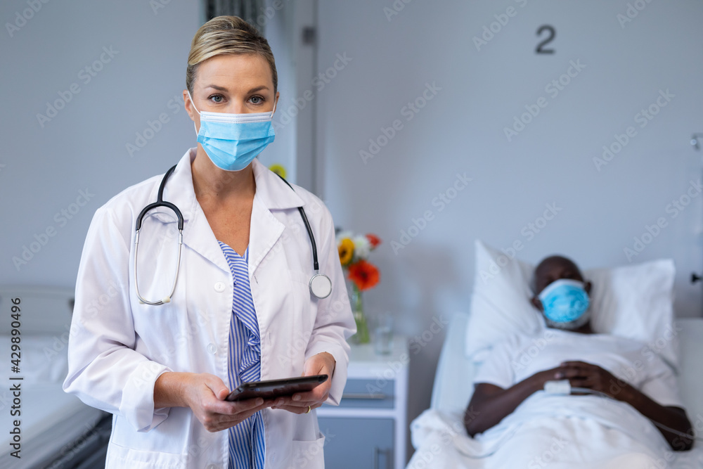 Wall mural Portrait of caucasian female doctor wearing face mask standing next to male patient