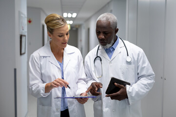 Diverse male and female doctors standing in hospital corridor looking at medical chart document