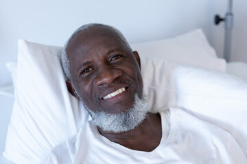 Portrait of african american male patient lying on hospital bed smiling to camera