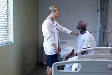 Caucasian female doctor smiling to african american male patient in hospital room
