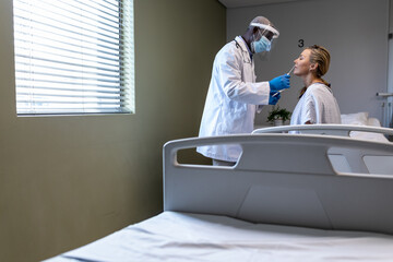 African american male doctor wearing face mask giving covid swab test to female patient