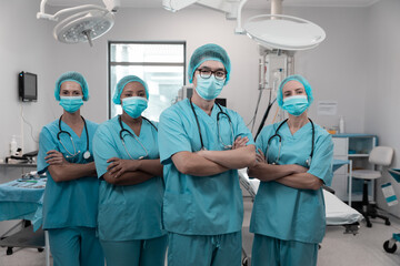 Diverse group of male and female doctors standing in operating theatre wearing face masks