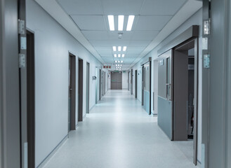 Empty, clean white corridor in modern hospital with overhead lighting, lined with doors
