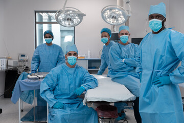 Diverse surgeons wearing face masks and protective clothing in operating theatre