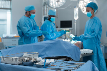 Diverse male and female doctors wearing face masks and surgical overalls in operating theatre