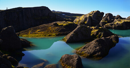 Fototapeta na wymiar A lone hiker admires the huge boulders and turquoise ponds on the Storurd hiking trail, East Fjords, Iceland 