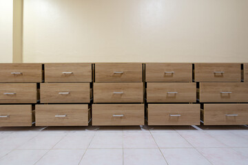 Wooden chest with open drawers against a cement wall background