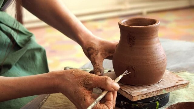 Female hands of a master potter prepares a place for a pot handle