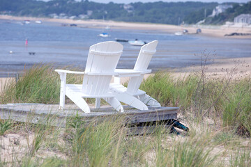 Two wooden beach chairs at the shore on Cape Cod in Wellfleet MA