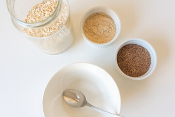 High angle closeup of bowl and spoon with oatmeal, brewers yeast and ground flaxseed (selective focus)