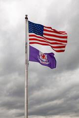 Flags of the United States of America and Talbot County, Maryland are flying together on a flag post against cloudy sky. Isolated image with copy space