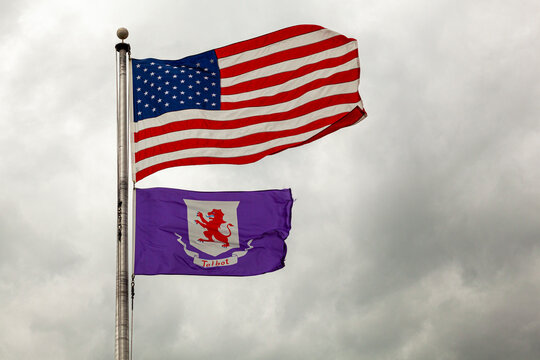 Flags of the United States of America and Talbot County, Maryland are flying together on a flag post against cloudy sky. Isolated image with copy space