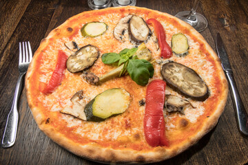 A vegetarian pizza on a plate on a wooden table.