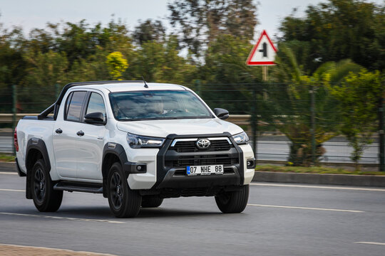 Alanya, Turkey &ndash; April 13 2021:  white pickup Toyota Hilux   is driving fast on the street on a warm summer day against the backdrop of a  palms