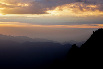 Mountain ridge on Huangshan mountain,Nature landscape view of Beautiful  sunset sky above clouds with dramatic light,Sunshine background landscape scene,View of mountains and valley on silhouette sun.