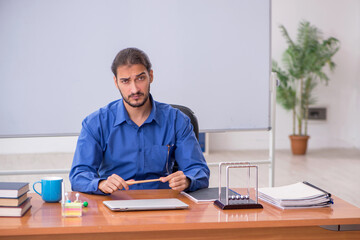 Fototapeta premium Young male teacher physicist sitting in the classroom
