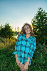 Portrait of a young beautiful blonde girl in a checkered shirt in the park.