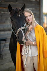 Portrait of beautiful blonde young woman with brown horse