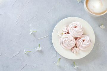 Homemade marshmallow on a plate with a cup of fresh morning coffee decorated with flowers.