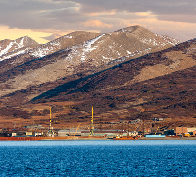 Autumn arctic industrial landscape. View from the sea to the cargo seaport and mountains. Port cranes and berths. Port infrastructure in the Far North of Russia. Beringovsky, Chukotka, Siberia, Russia
