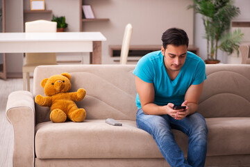 Young man sitting with bear toy at home