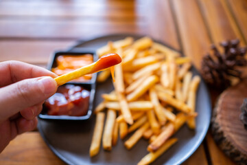 The hand was picking the French flies dipped in tomato sauce