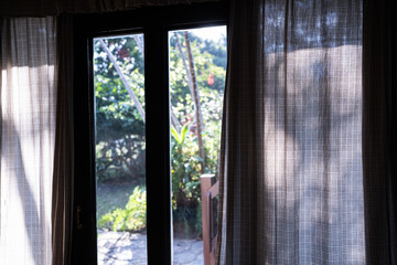 Window with curtains,Window with a view onto fields and trees in a rural setting. Curtains and a...