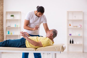 Old male patient visiting young male doctor chiropractor