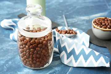 Jar with chocolate corn balls on color background