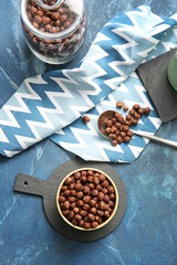 Bowl and spoon with chocolate corn balls on color background