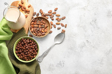 Bowls with chocolate corn balls and cocoa beans on light background