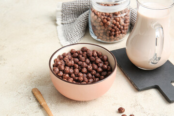 Fototapeta na wymiar Bowl with chocolate corn balls and jug of milk on light background