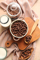 Bowl with chocolate corn balls and glass of milk on color background