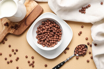 Bowl with chocolate corn balls on color background