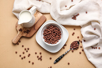 Bowl with chocolate corn balls on color background