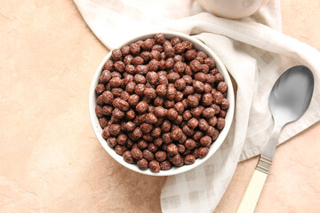 Bowl with chocolate corn balls on color background