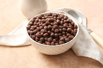Bowl with chocolate corn balls on color background