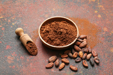 Bowl and scoop with cocoa powder and beans on grunge background