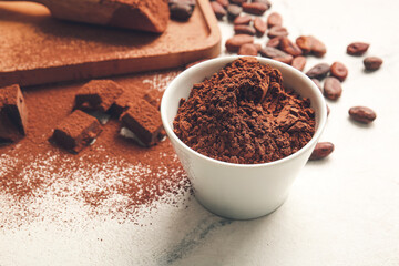 Bowl with cocoa powder on light background