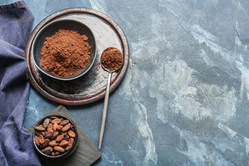 Bowls with cocoa powder and beans on color background