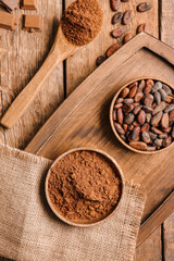 Bowls with cocoa powder and beans on wooden background