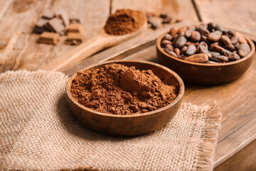 Bowls with cocoa powder and beans on wooden background