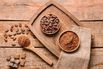 Bowls with beans and cocoa powder on wooden background