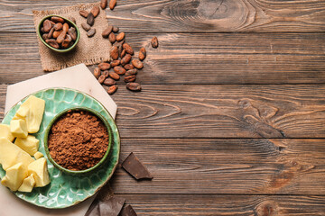 Composition with cocoa powder, beans, butter and chocolate on wooden background