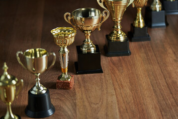 row of trophy on the wooden table against dark gray background