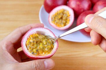 Man's Hand Scooping Fresh Ripe Passion Fruit from Its Shell with a Spoon