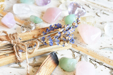 A close up image of Palo Santo incense sticks with dried lavender and healing crystals on a white background. 
