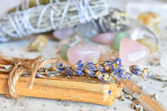 A close up image of Palo Santo incense sticks with dried lavender and healing crystals on a white background. 