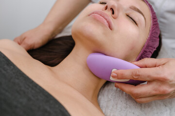 Obraz na płótnie Canvas Young woman receiving anti-aging rejuvenation machine massage in spa salon